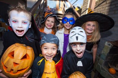 Kids dressed up in costumes holding carved pumpkins