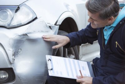 Insurance adjuster evaluating damage to car's bender