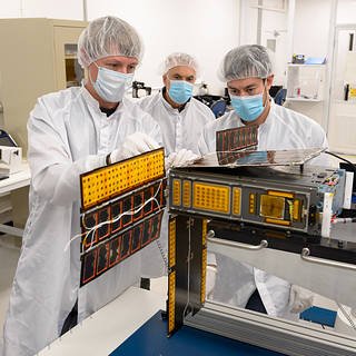 Abraham Rademacher, left, Vaslie Manolescu, and James Milsk perform a solar array deployment and gimbal motion test on BioSentinel’s flight unit in BioSentinel Lab’s clean room, N213 room 104.