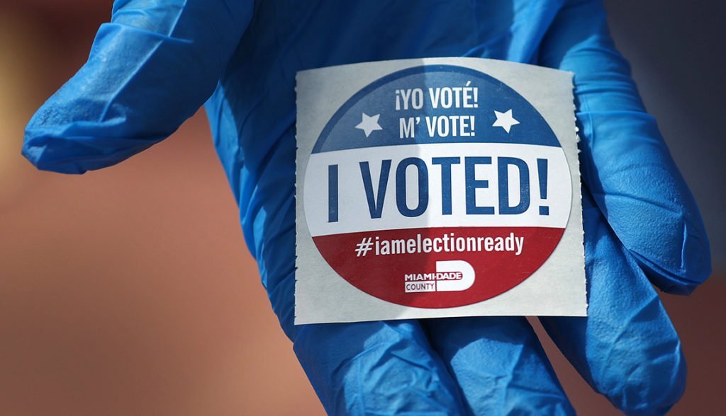 MIAMI BEACH, FL  - MARCH 17:  A voter holds an, 'I Voted!', sticker after wearing a glove as she cast her ballot during the Florida presidential primary as the coronavirus pandemic continues on March 17, 2020 in Miami Beach, Florida.  People are heading to the polls to vote for their Republican and Democratic choice in their parties’ respective primaries during the COVID-19 outbreak. (Photo by Joe Raedle/Getty Images)