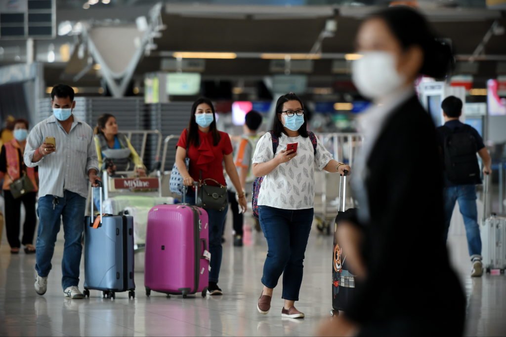 Bangkok, Thailand - February 18, 2020: Air travelers wearing masks walk through departures hall of Suvarnabhumi Airport. Thailand has been assessed as a country at risk of Covid-19 outside of China.