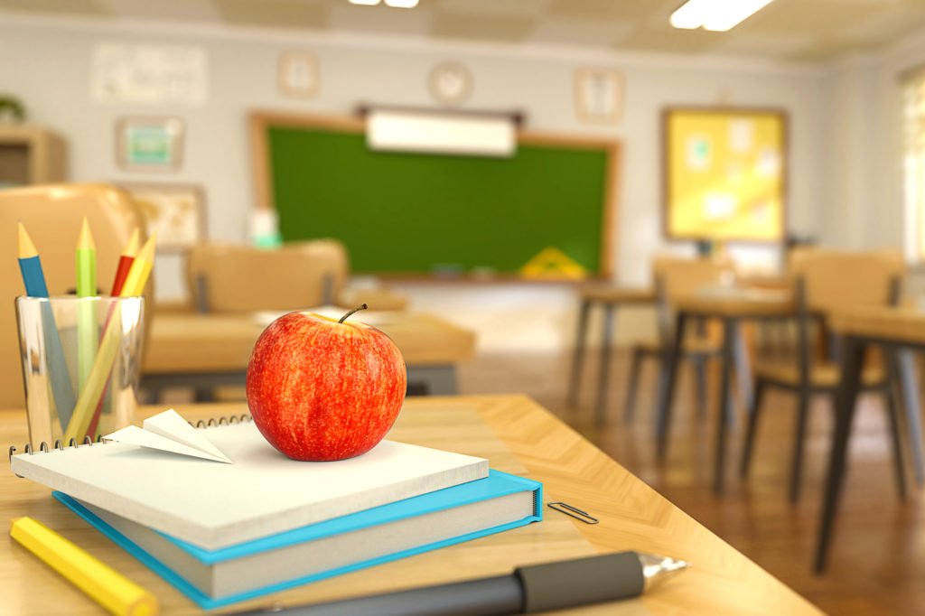 Book, pen, pencils and red apple on table in empty school classroom. 3D rendering illustration. Back to school background templateCartoon style school elements - book, pen, pencils and red apple on desk in empty classroom. 3D rendering illustration. Back to school design template.