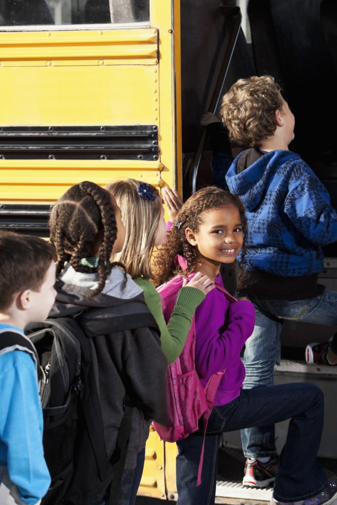 Multi-ethnic elementary students (ages 5 to 9) boarding school bus.