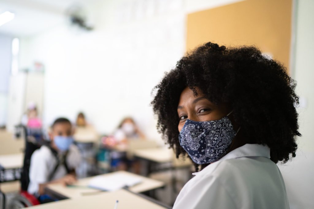Portrait of teacher working in classroom using face mask