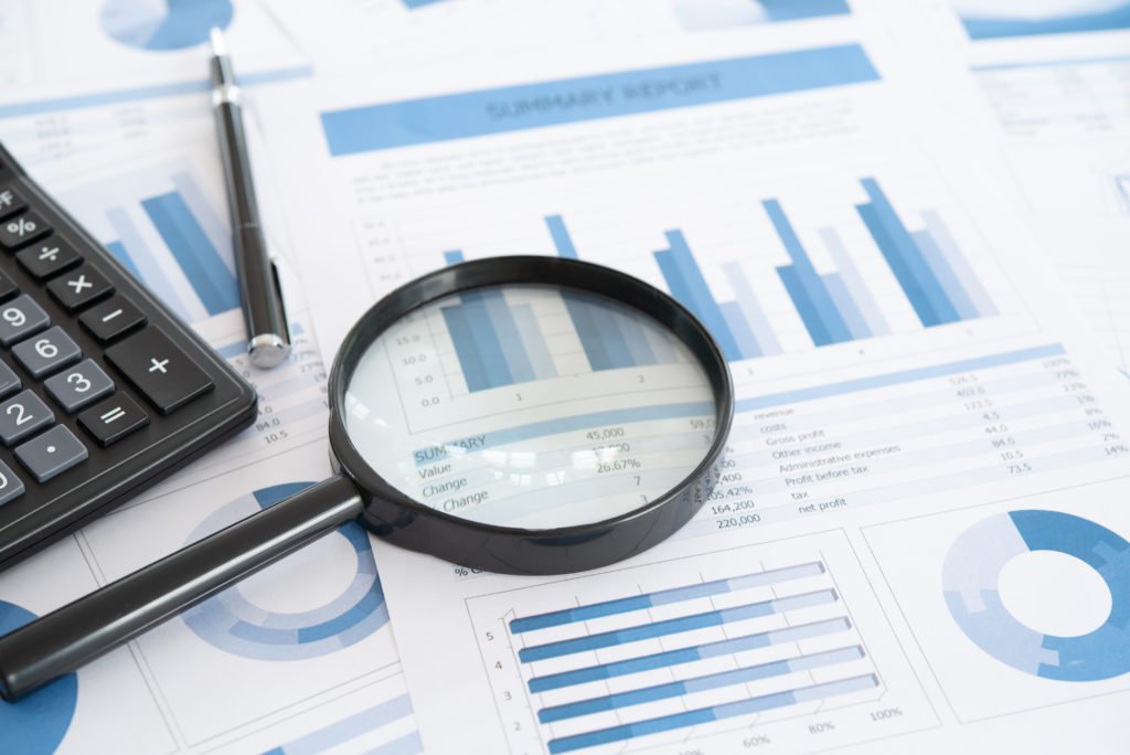 business and investment planning. Magnifying glass with business report on financial advisor desk. Concept of data analysis, accounting,audit, business research.