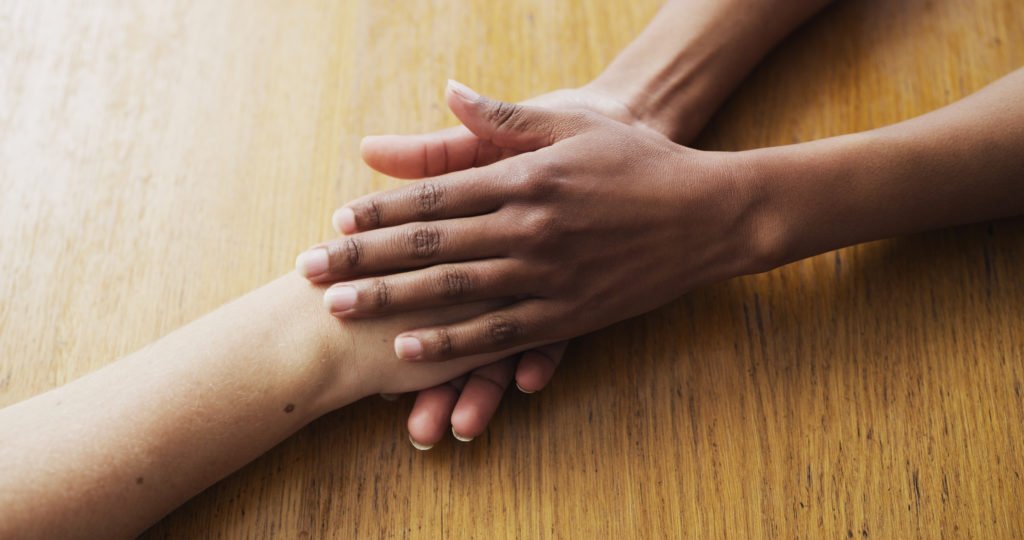Closeup shot of two unrecognisable people holding hands in comfort