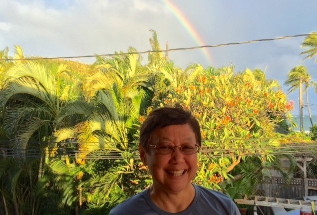 Vanee Songsiridej with rainbow and palm trees in background. Mindfulness, Health, and Community