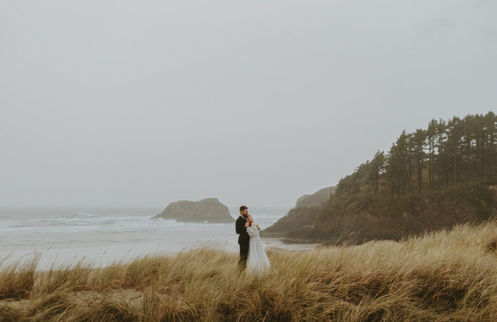 A couple holds each other on a cloudy coast line.