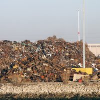 Pile of trash at Recycling processing facility along shore of Oakland Harbor, California during the day.