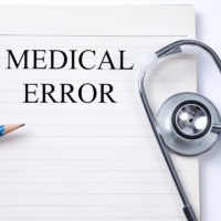 Stethoscope on notebook and pencil with Medical Error words